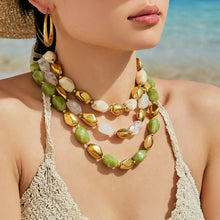 Model wearing layered green and neutral resin bead necklaces with gold stainless steel accents