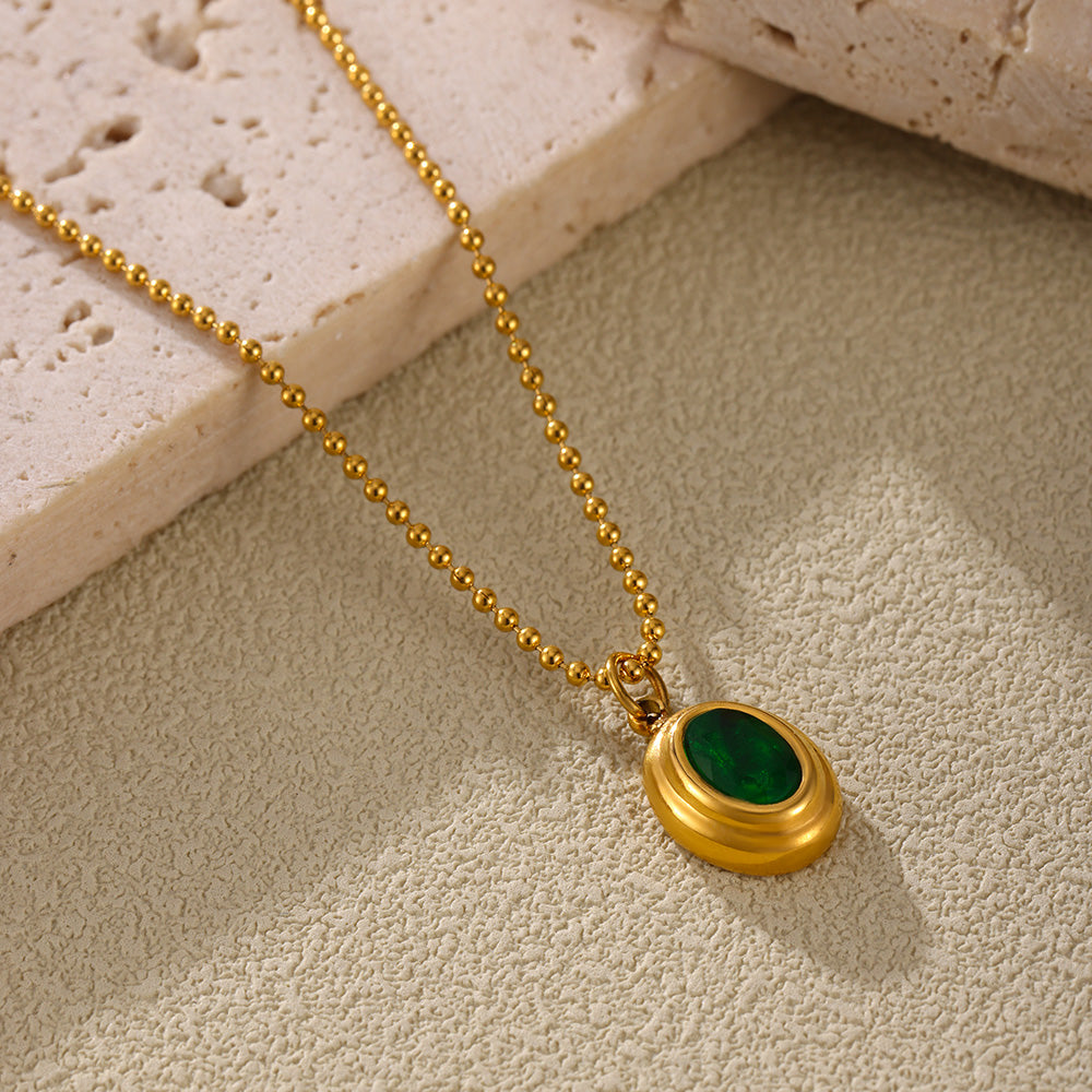 Close-up of a green oval zircon pendant necklace on a beige jewelry display
