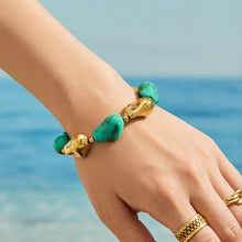 Green chunky resin bracelet with organic beads and sculptural gold accents worn on the wrist