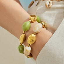 Close-up of green white and gold organic resin bracelets stacked on a model wrist