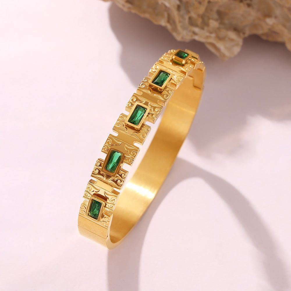Closeup of 18K gold green zircon clasp bangle, carved pattern & gemstone inlay