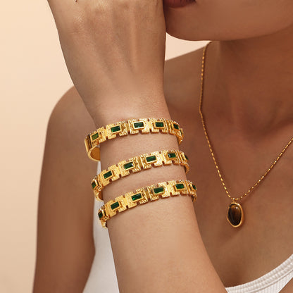 Model wearing stacked 18K gold green zircon clasp bangles, trendy layered gemstone accessory