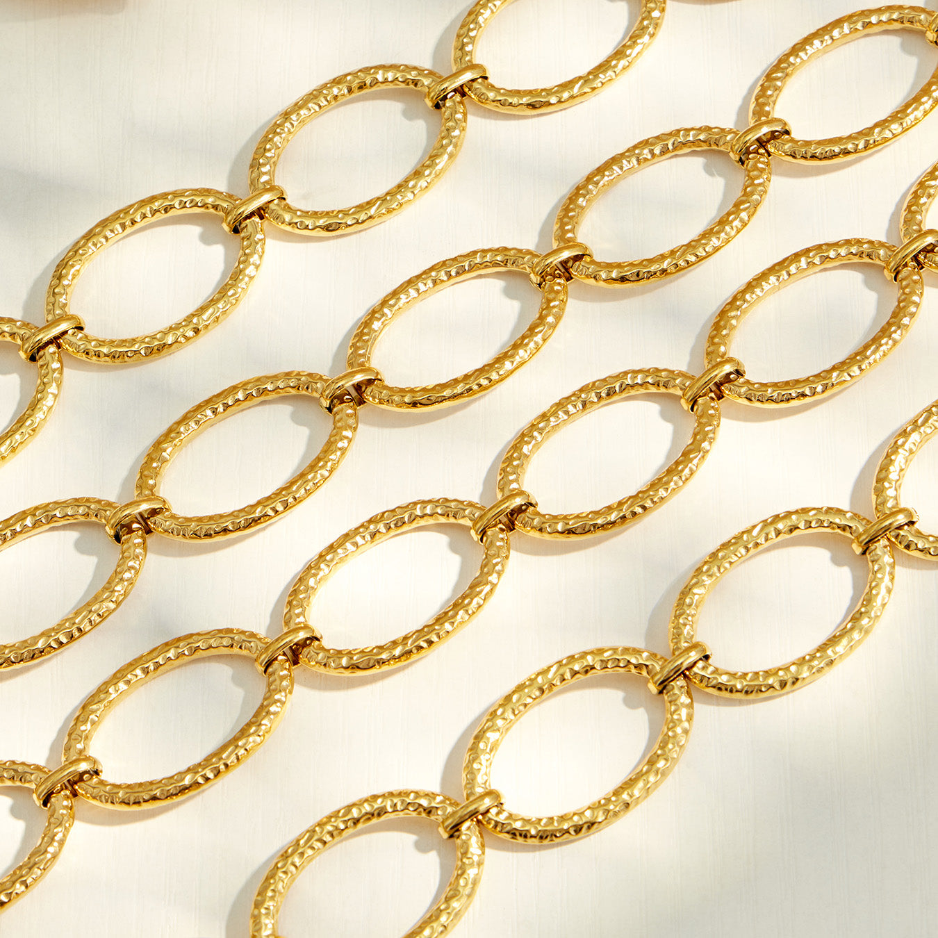 Close-up of textured hammered oval links on a gold chain necklace and bracelet