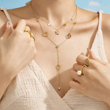 Model wearing layered gold heart and butterfly lariat necklaces with a white outfit