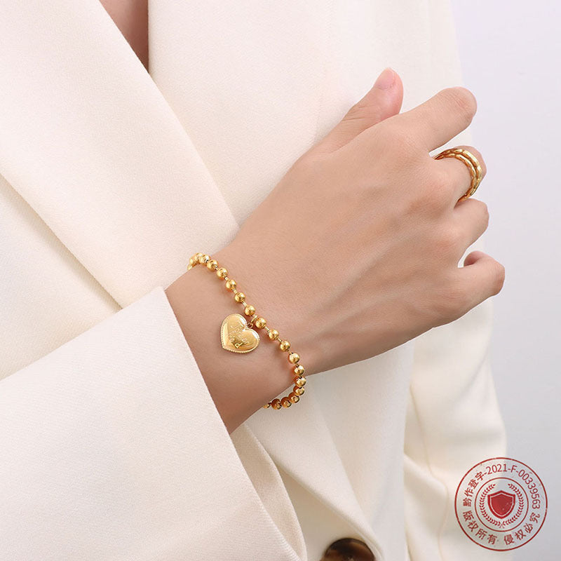 Close-up of an engraved heart charm bracelet worn on the wrist
