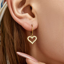 Close-up of gold heart cubic zirconia earrings with open heart design
