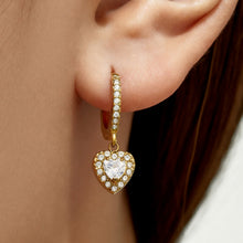 Close-up of gold heart CZ charm huggie earrings with clear cubic zirconia