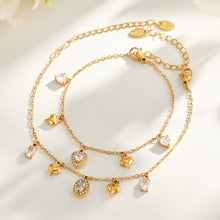 Heart and oval zircon charm bracelets in gold-tone stainless steel displayed together