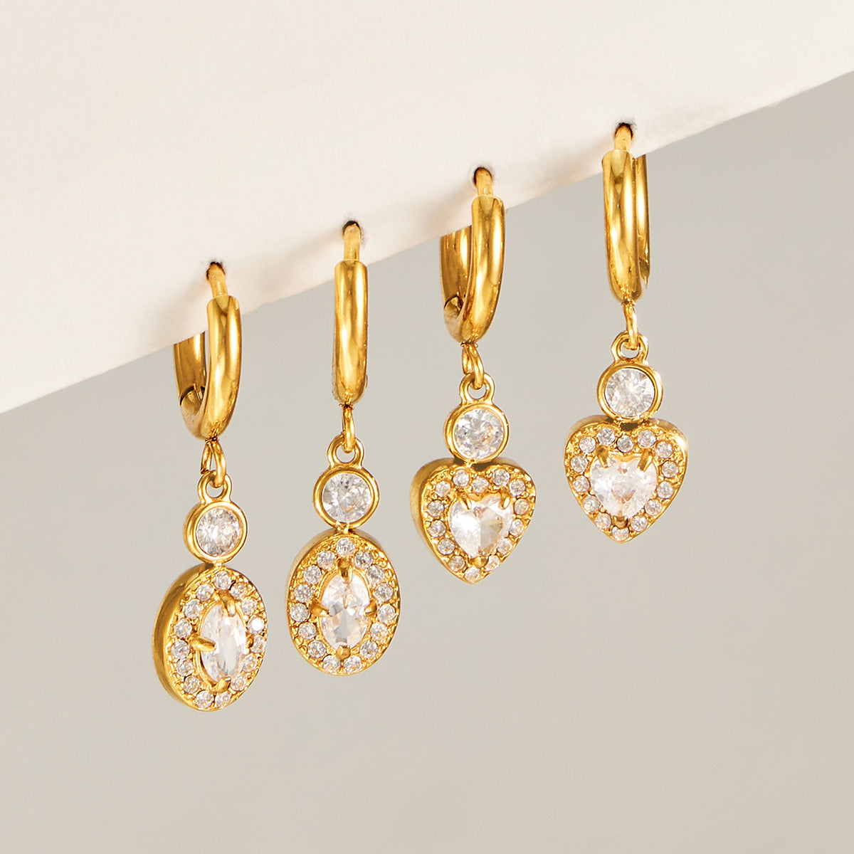 Gold heart and oval zircon hoop earrings displayed in matching charm styles