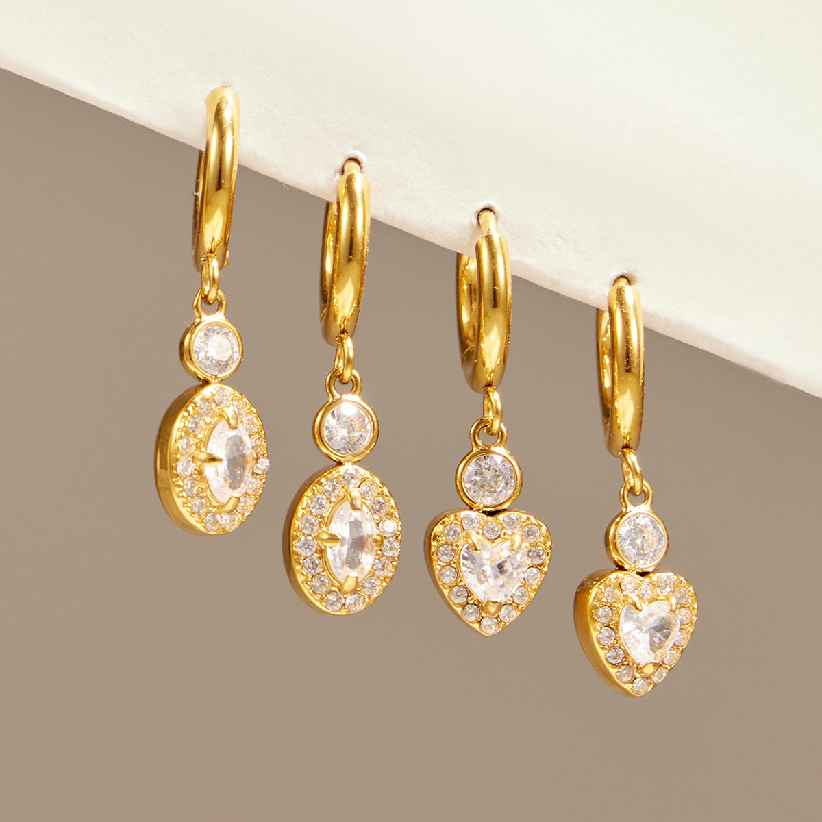 Gold heart and oval zircon hoop earrings shown together as matching jewelry styles