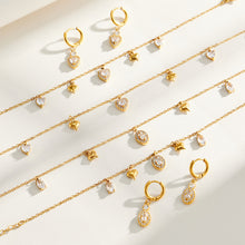 Heart and oval zircon charm necklaces, bracelets and earrings displayed together in gold tone