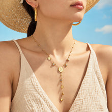 Gold-tone heart Y necklace with coin and zircon details worn on model