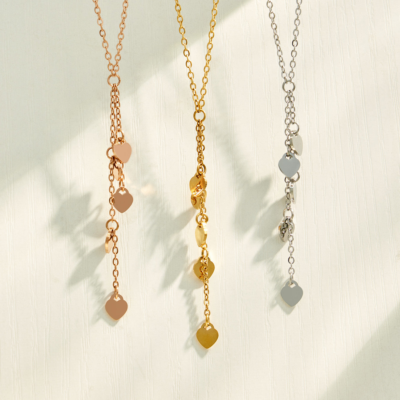 Heart tassel Y necklaces displayed in gold, polished steel and rose gold finishes