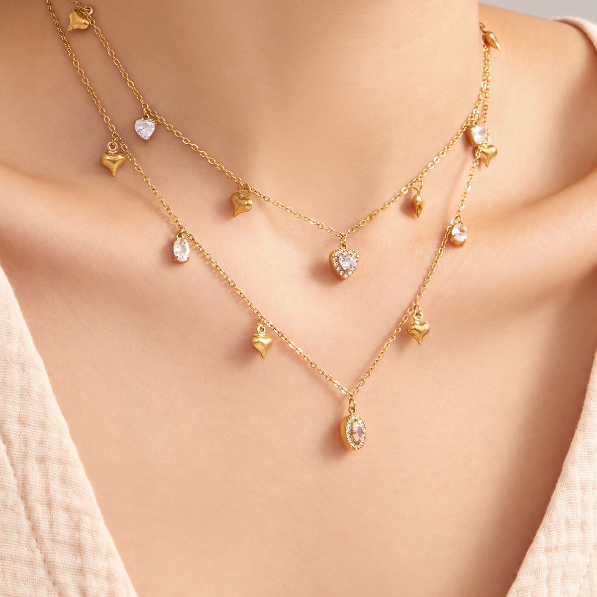 Gold heart and oval zircon charm necklaces with spaced drop details worn on model
