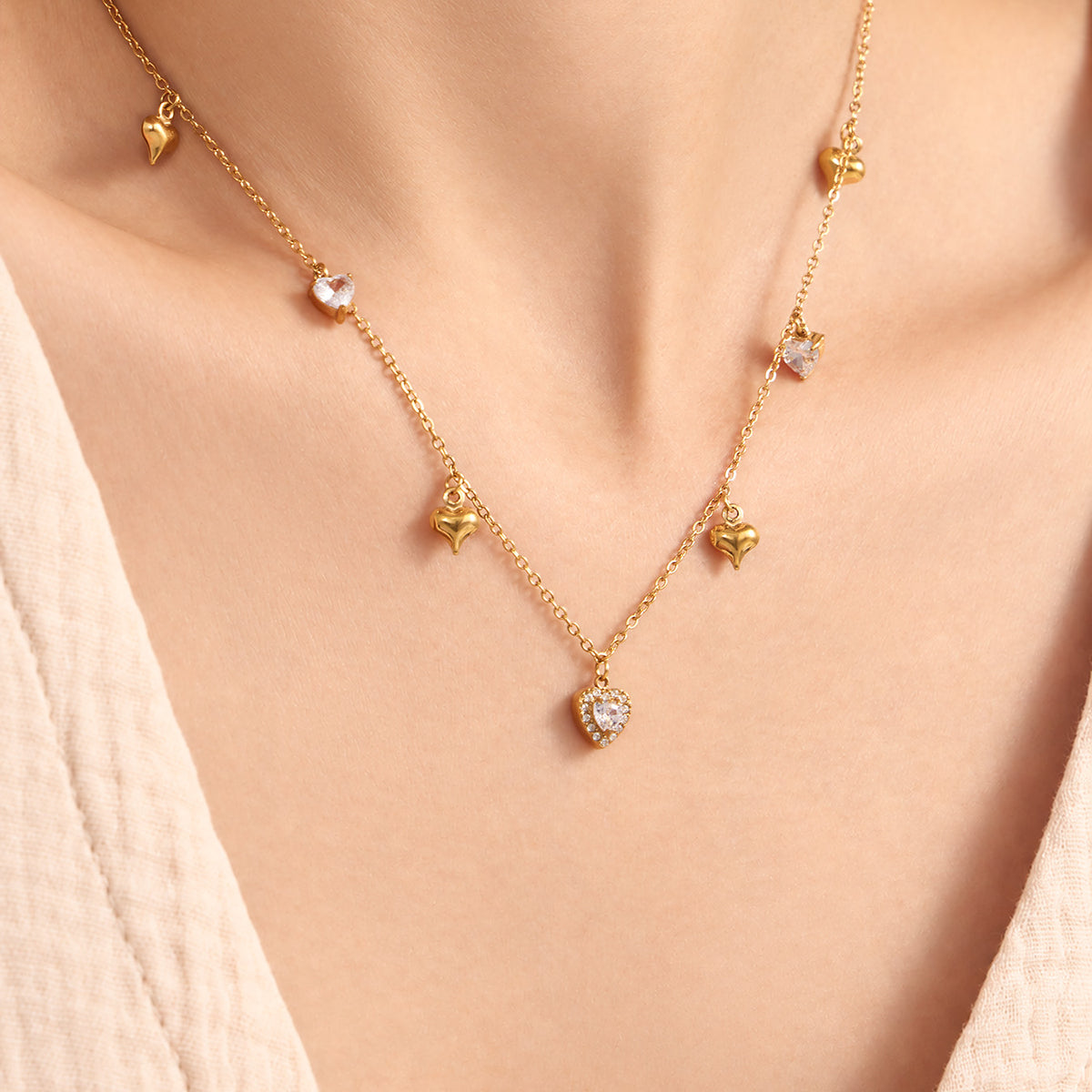Gold heart zircon charm necklaces with delicate station-style drops layered at the neckline
