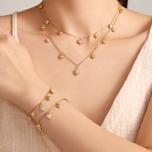 Gold-tone heart and oval zircon charm necklaces and matching bracelets layered on model