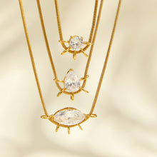 Close-up of round, teardrop and marquise zircon pendants layered on gold-tone chains