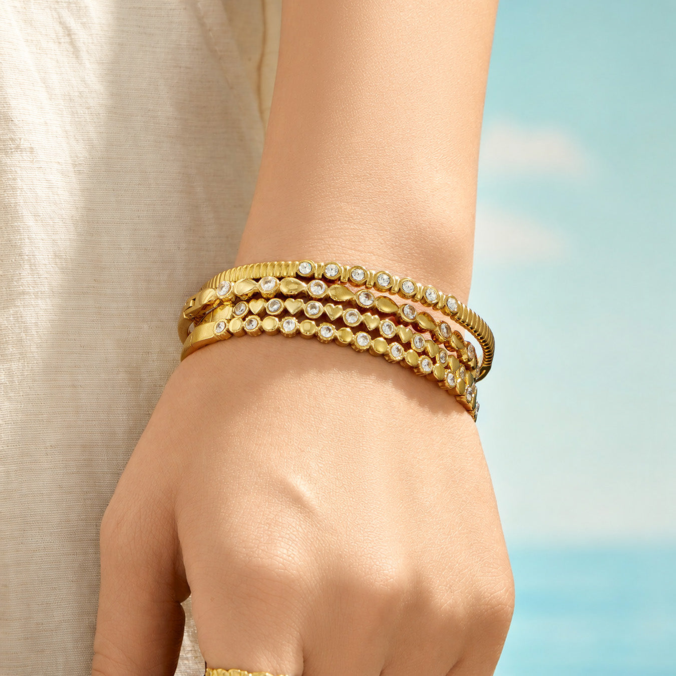 Layered gold geometric bangles styled on a model hand