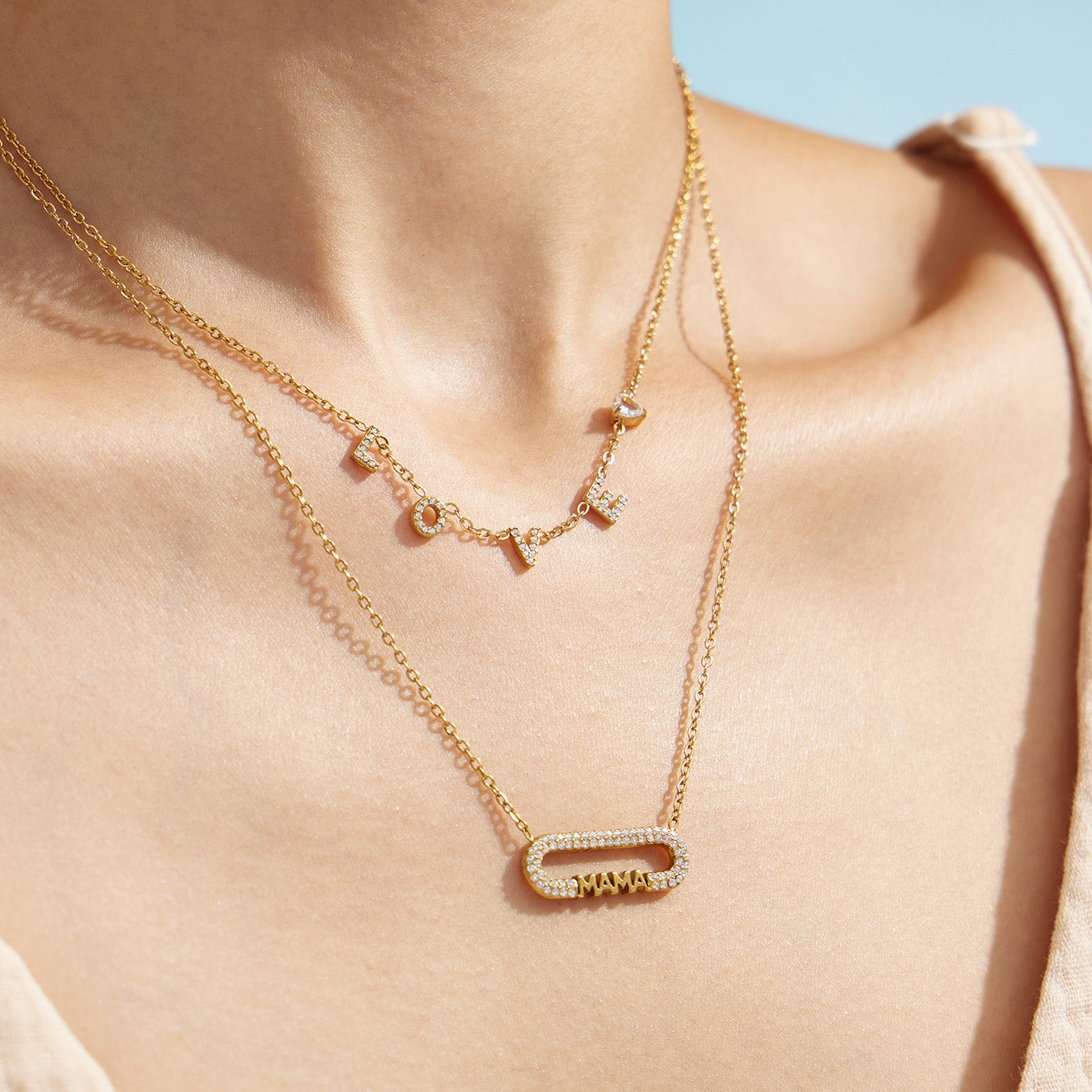 Layered gold necklaces featuring a small letter chain and MAMA zircon bar necklace