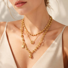 Model styling layered gold minimalist necklaces with chain and pendant details