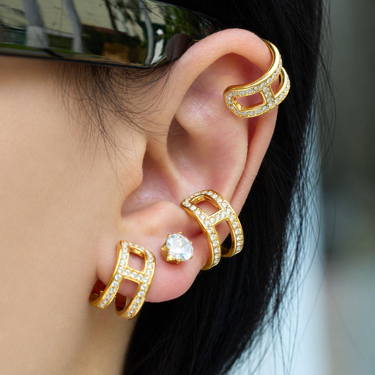 Layered gold-tone stainless steel rhinestone ear cuffs worn for a stacked ear look