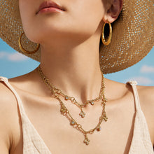 Layered gold teardrop necklaces styled together on a model