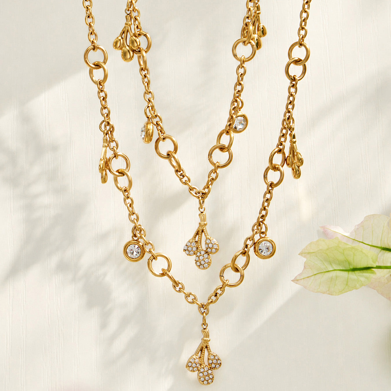 Two gold teardrop zircon necklaces layered together on a light background