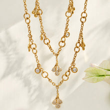 Two gold teardrop zircon necklaces layered together on a light background