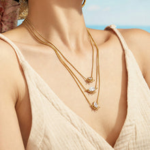Model neckline showing three layered gold-tone zircon pendant necklaces