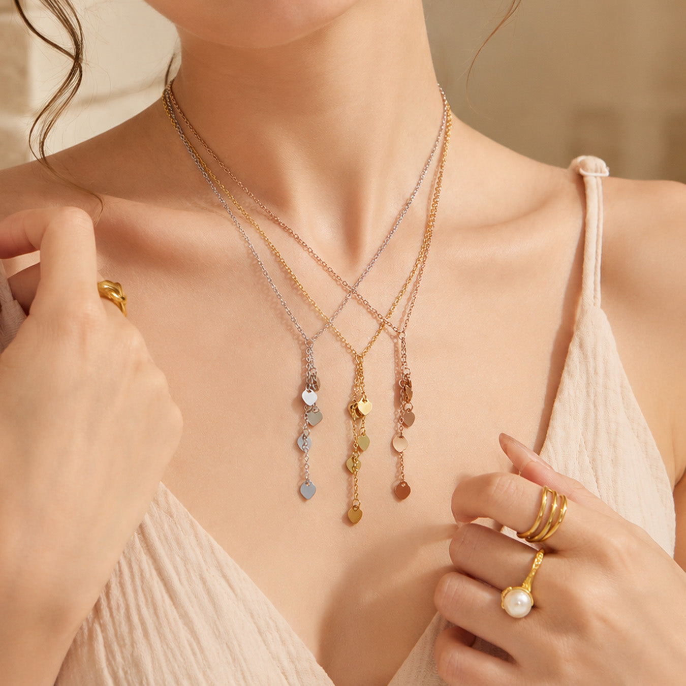 Model styling a gold heart Y necklace with layered chains at the neckline