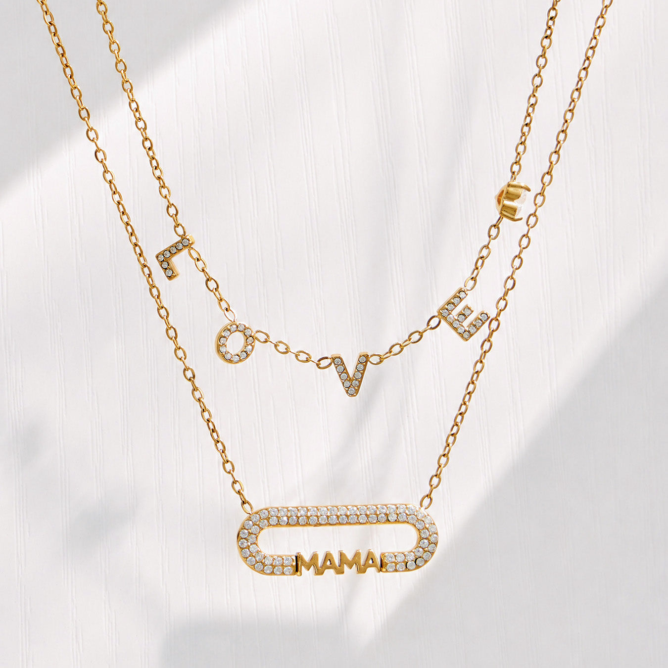 Model wearing a layered gold necklace arrangement with a MAMA zircon bar pendant