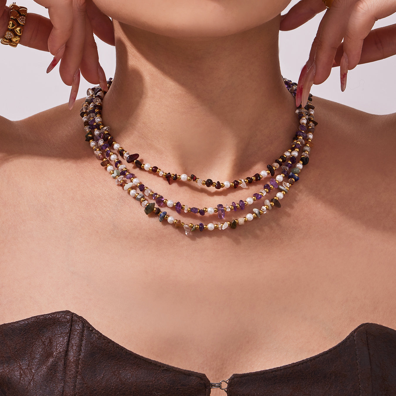 Close-up of a layered natural stone and freshwater pearl necklace worn by a model