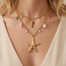 Layered ocean charm necklace with starfish, shell and fish details on model