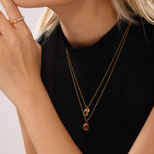 Layered gold necklaces with red zircon pendants styled over a black top