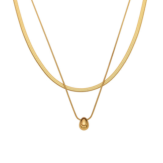 Layered gold tone stainless steel necklace with snake chain and teardrop pendant on white background