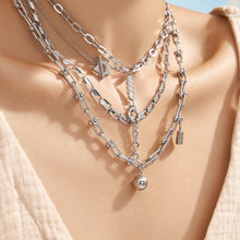 Model wearing layered polished steel minimalist necklaces with chain and toggle details
