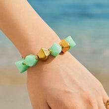 Light green faceted resin bead bracelet with gold stainless steel accents worn on a model wrist