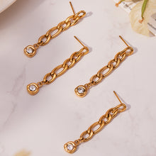 Long gold link chain zircon drop earrings arranged diagonally on a light background
