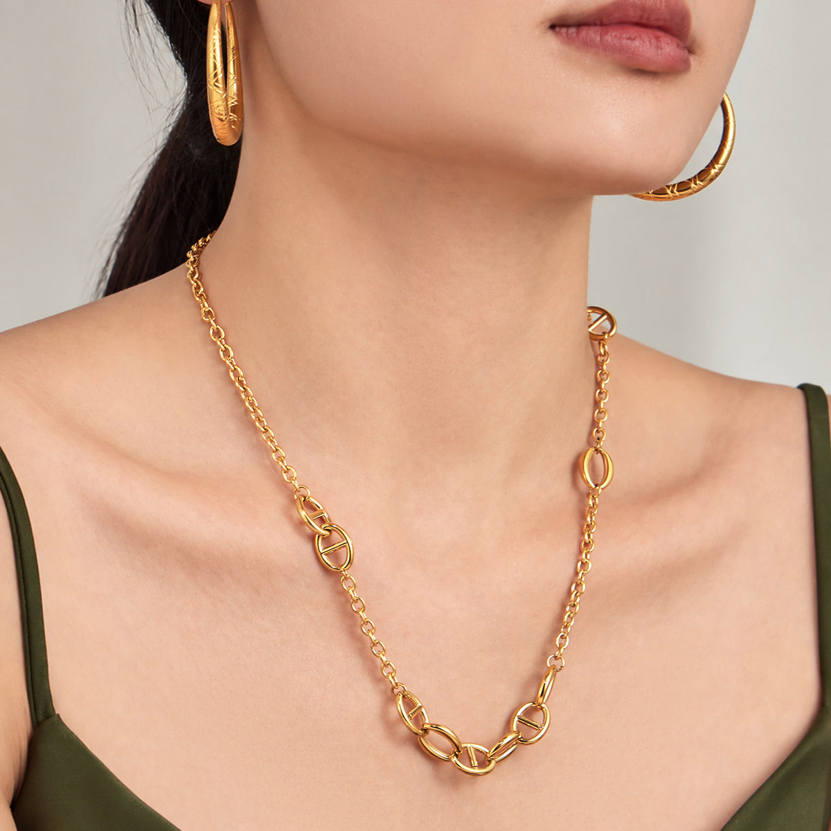 Gold geometric link necklace styled at a longer length on model