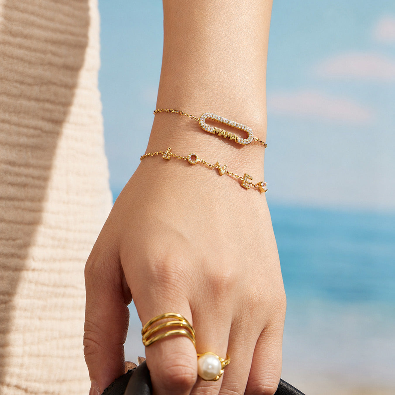 Gold MAMA zircon bar bracelet worn on a model wrist in an outdoor setting