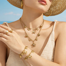 Matching gold butterfly charm necklace and floral bracelet styled together on a model