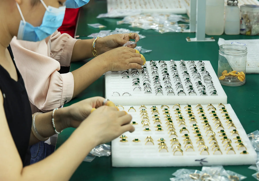 Staff handling jewelry pieces arranged in trays