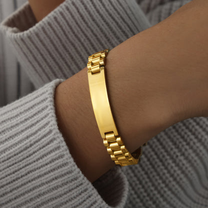 Men’s gold ID link bracelet worn on wrist with polished center plate and structured stainless steel links for boutique buyers