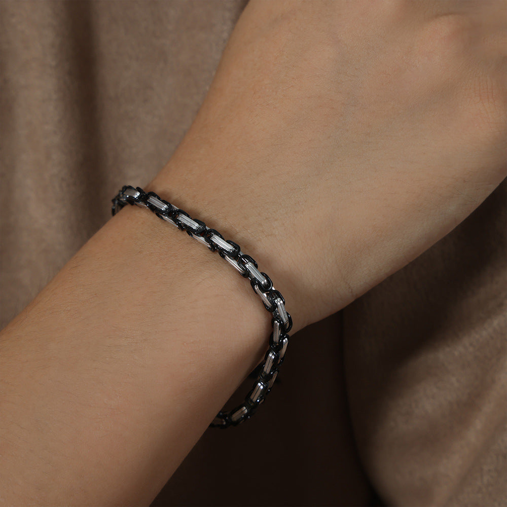 Men’s black steel link chain bracelet worn on wrist with polished stainless steel details for street-style jewelry buyers