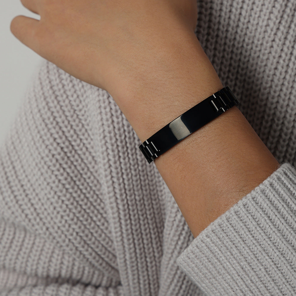 Men’s black steel ID link bracelet worn on wrist with bold polished plate for street-style men’s jewelry collections