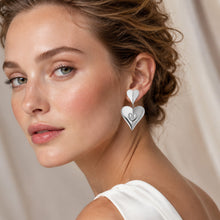 Ear close up of gold heart zircon drop earrings with lightweight double heart drop design