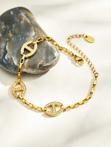 Gold D-shaped zircon bracelet flat lay with adjustable lobster clasp and geometric charm details