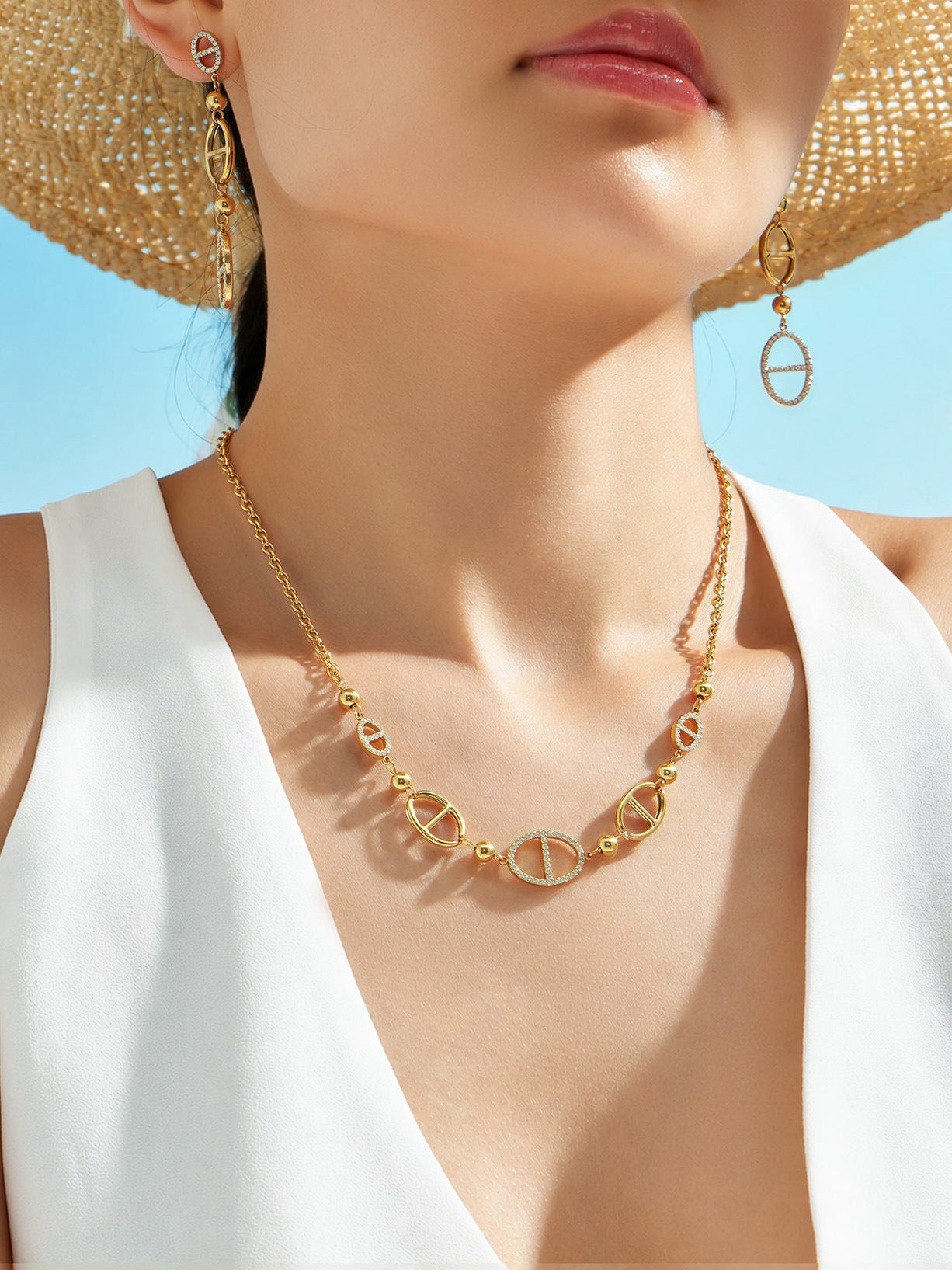 Close up of gold geometric zircon chain links with oval charm details for necklace and bracelet set
