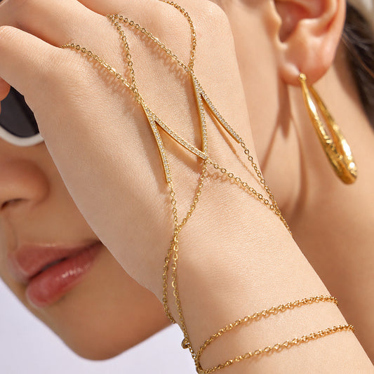 Close-up of gold V-shaped zircon hand chain bracelet worn across hand and wrist, dainty hand harness bracelet for boutique wholesale buyers