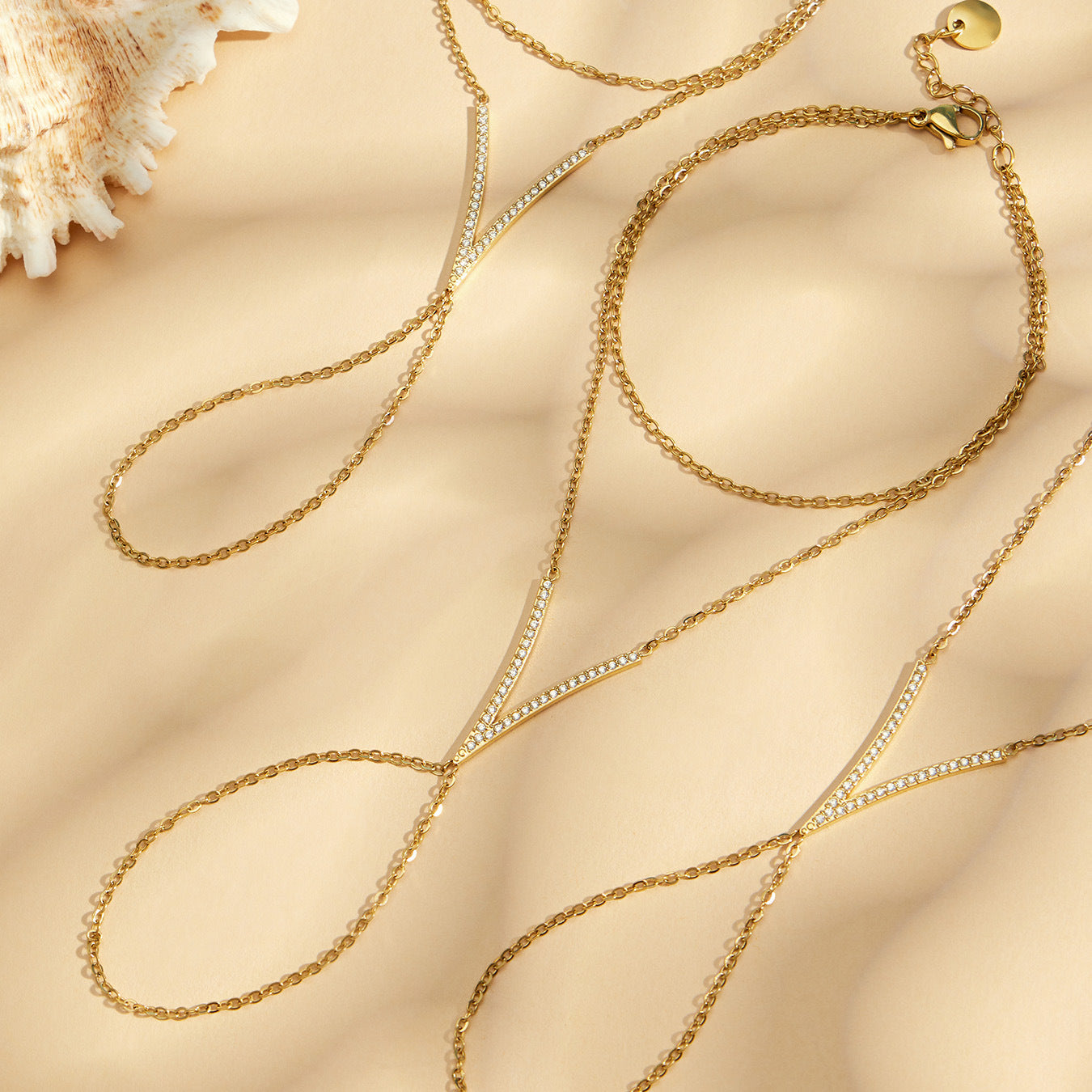 Gold zircon hand chain bracelet with V-shaped sparkling zircon bar and dainty finger-to-wrist chain, beach flatlay by Miduoduo Jewelry